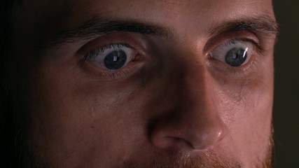 Obraz premium Gray eyes of surprised intelligent young man using his tablet PC. Screen reflecting, device lighting glow in the dark