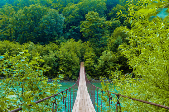 Fototapeta Suspension bridge over the stormy mountain river