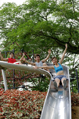 Group of young people sliding down playground slide