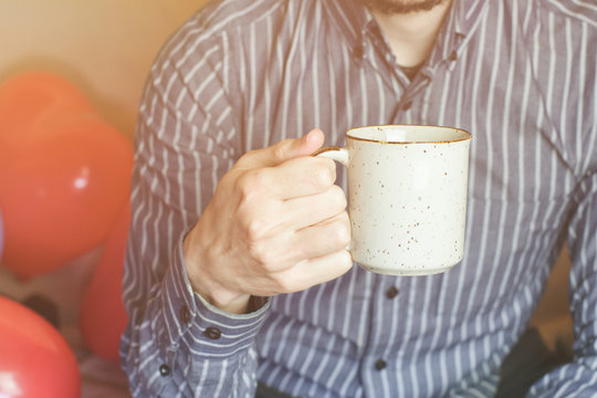 Hombre joven desayunando una taza de una bebida caliente 