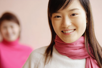 Obraz premium Young woman with scarf smiling, another woman in background