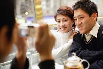 Couple posing as another person takes their picture