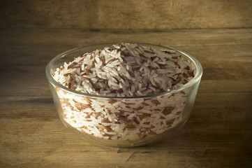 Rice in a bowl placed on the old wooden floor low key light.