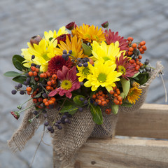 Autumn bouquet of yellow, orange, brown carnations with eucalyptus in a vase wrapped by canvas as decoration street market