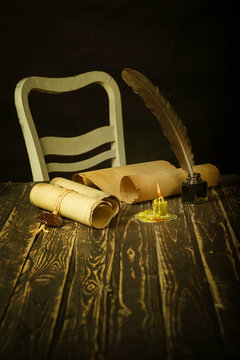 Papyrus scrolls on a wooden table with an inkwell, pen and shine