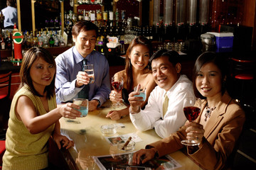 Group of people raising wine glasses, looking at camera