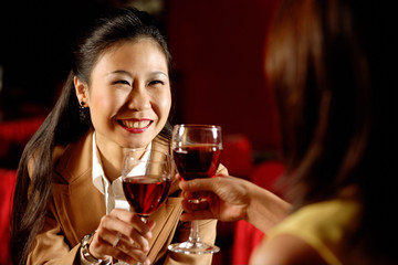 Two women toasting with wine glasses.