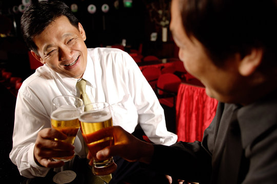 Two men face to face, holding beer glasses