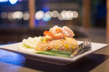 Shrimp fried rice dish is placed on a wooden table. Appetizing b