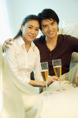 Couple looking at camera, champagne glasses in front of them