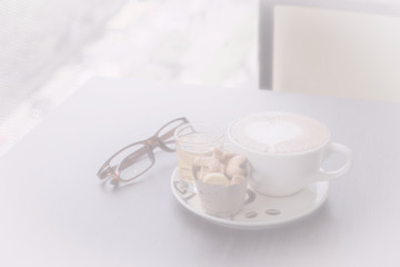 hot fresh coffee in white glass hot tea and alphabet biscuit glasses with tree shape of heart foam in white tone on wooden table city view at sunset at coffee time / hot fresh coffee white tone