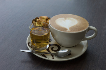 hot fresh coffee in white glass hot tea and alphabet biscuit with tree shape of heart foam on wooden table city view at sunset at coffee time / hot fresh coffee and tea