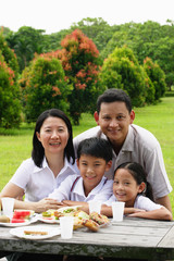 Family seated at picnic table, portrait