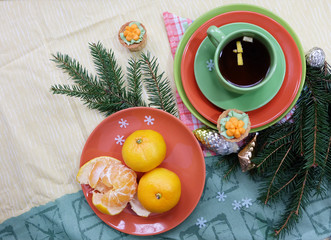 Christmas tea. A cup of tea, tangerines, cakes and fir branches with New Year's decor.