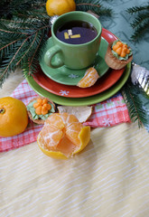Christmas tea. A cup of tea, tangerines, cakes and fir branches with New Year's decor.
