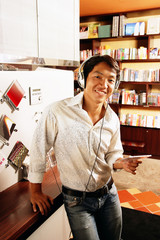 Young man listening to music, smiling, looking at camera