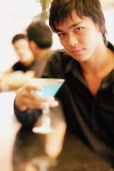 Young man at bar counter holding cocktail glass