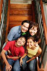 Family of four sitting on stairs, looking at camera, portrait