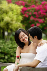 Fototapeta premium Couple sitting on park bench, looking at each other