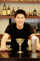 Man behind bar counter, glass and mixer in front of him