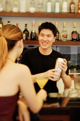 Man holding cocktail mixer, woman in front of him