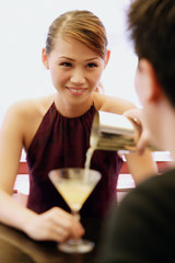 Man pouring drink for woman