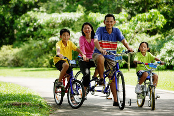 Family in park, riding bicycles, looking at camera