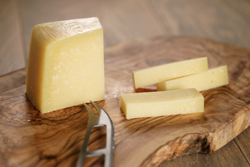 cutted parmesan cheese on olive cutting board
