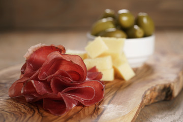 classic italian antipasti, breasola. olives and parmesan on olive board