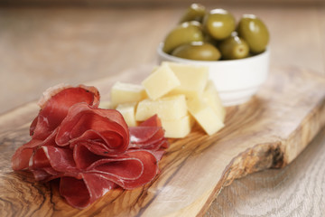 classic italian antipasti, breasola. olives and parmesan on olive board