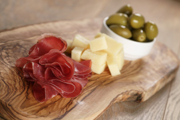 classic italian antipasti, breasola. olives and parmesan on olive board