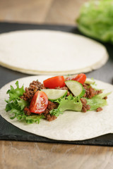 open tortilla with beef, frillice and vegetables