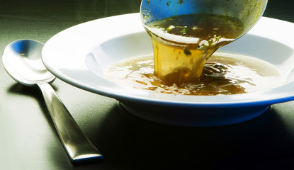 Ladle broth to the pan with the broth background top view 