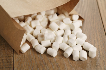 Fototapeta na wymiar marshmallow in brown craft paper bag on wooden table