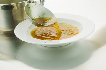 Ladle broth to the pan with the broth background top view 