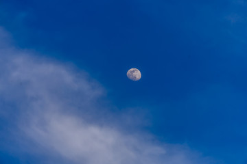 Moon and blue sky with some white clouds.