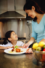 Mother holding plate and looking down at daughter