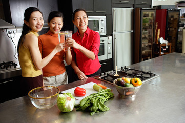Women in kitchen, toasting, smiling at camera