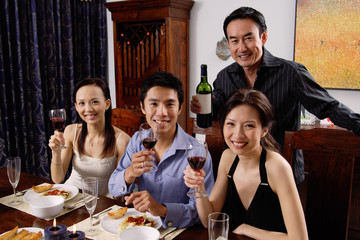 Adults at dining table, smiling at camera, raising wine glasses
