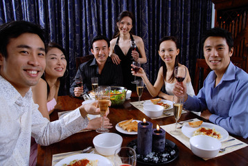 Couples at a dinner party, smiling at camera