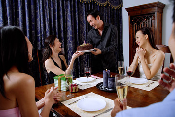 Party at home, women accepting birthday cake from man