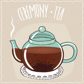 Fototapeta Transparent glass teapot with hot brewed black tea, lie on a lacy napkin. Beige background and ornate lettering Ceremony tea. Handmade cartoon style