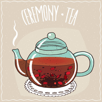 Fototapeta Transparent glass teapot with hot brewed tea rosehip, lie on a lacy napkin. Beige background and ornate lettering Ceremony tea. Handmade cartoon style