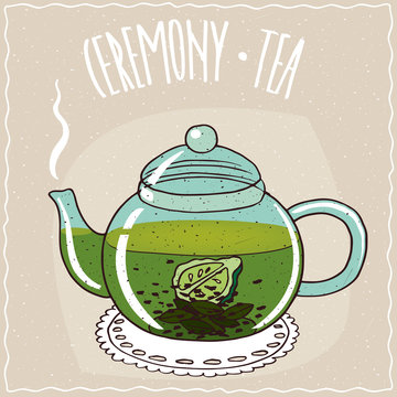 Fototapeta Transparent glass teapot with hot brewed tea with bergamot, lie on a lacy napkin. Beige background and ornate lettering Ceremony tea. Handmade cartoon style