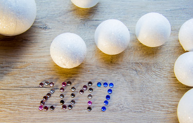 Fototapeta na wymiar many small white balls toys symbol of the new year on a wooden , top view, there is a place for text as the background and the substrate, there are numbers of new 2017