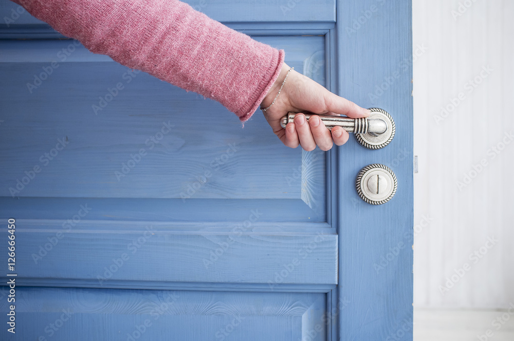 Wall mural man holding a metal pen in an open wooden door blue