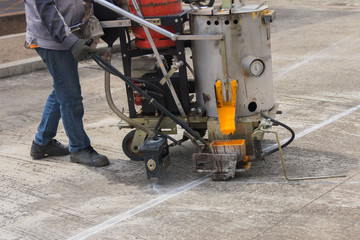 Man painting the yellow line on the concrete floor at car park