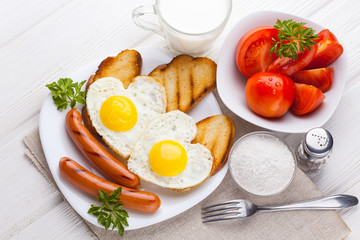 Breakfast on Valentine's Day - fried eggs in the shape of a heart and sausages. Top view