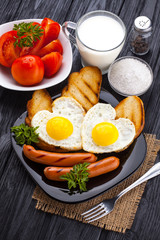 Breakfast on Valentine's Day - fried eggs in the shape of a heart and sausages. Top view