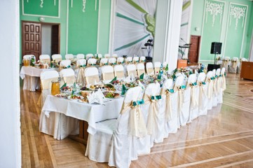 Decorated wedding chairs with golden and green velvet ribbons